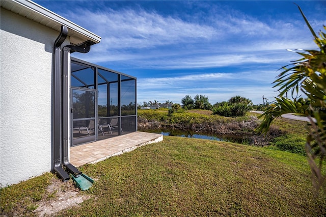 view of yard featuring glass enclosure, a water view, and a patio