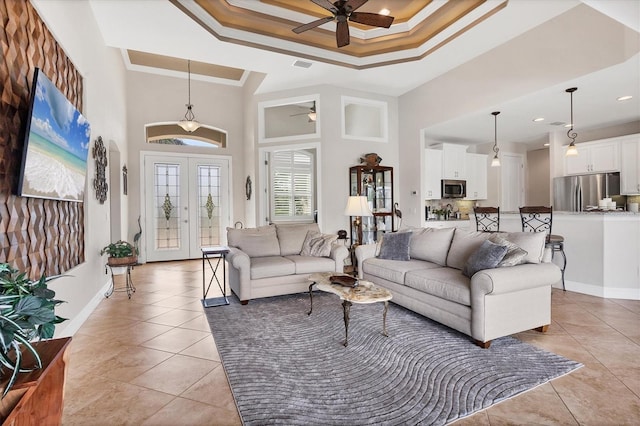 tiled living room featuring ceiling fan, crown molding, a high ceiling, and a tray ceiling