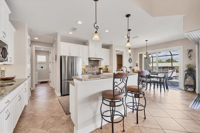 kitchen with appliances with stainless steel finishes, white cabinetry, a kitchen island with sink, and pendant lighting