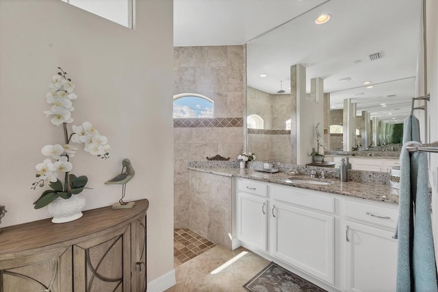 bathroom featuring tiled shower, vanity, tile walls, and tile patterned flooring