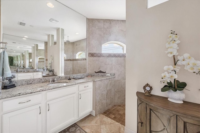 bathroom with vanity, tiled shower, and tile walls