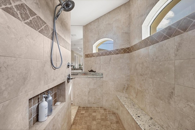 bathroom featuring a tile shower and a healthy amount of sunlight