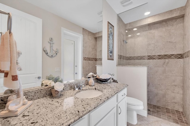 bathroom with tile patterned floors, vanity, toilet, and tiled shower