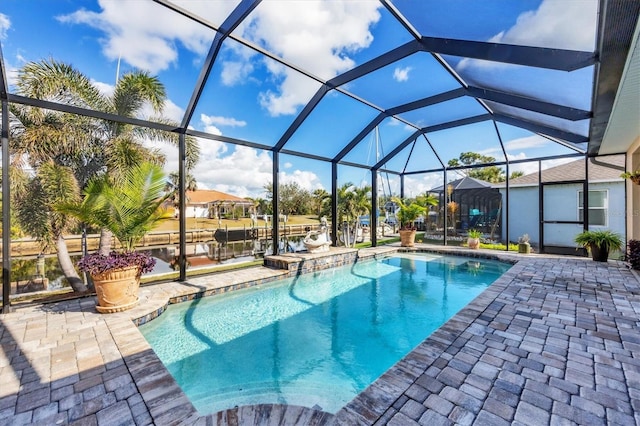 view of pool with glass enclosure, a water view, and a patio