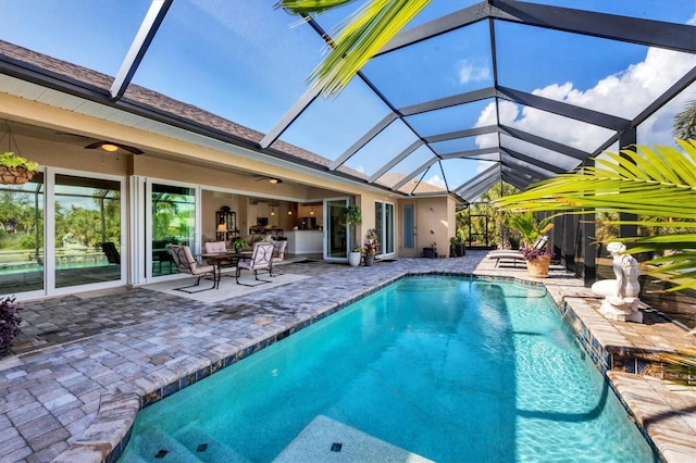 view of swimming pool featuring pool water feature, ceiling fan, a lanai, and a patio