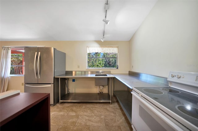 kitchen featuring stainless steel fridge, white electric range oven, track lighting, stainless steel counters, and a wealth of natural light