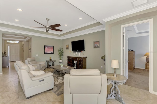 living room featuring ceiling fan, light colored carpet, ornamental molding, and a tray ceiling