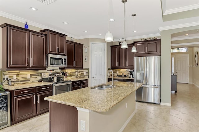 kitchen with appliances with stainless steel finishes, tasteful backsplash, a kitchen island with sink, sink, and pendant lighting