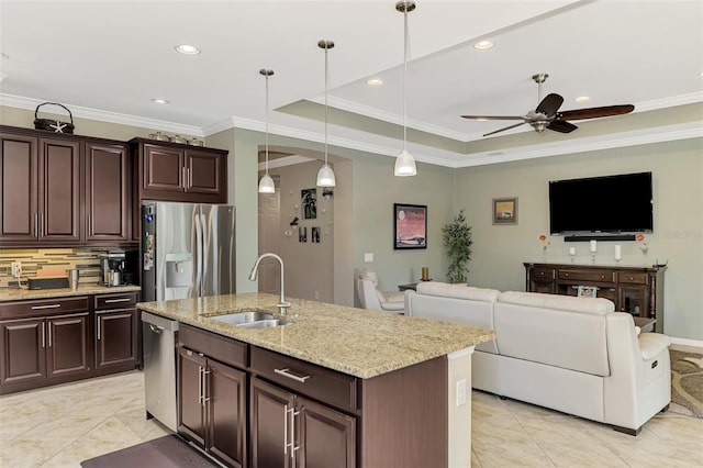 kitchen with stainless steel appliances, a tray ceiling, sink, pendant lighting, and a center island with sink