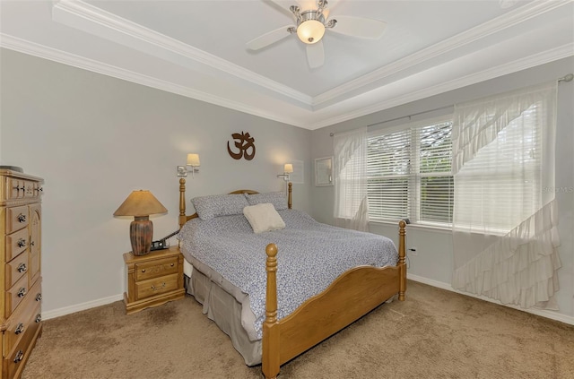 carpeted bedroom with a tray ceiling, ceiling fan, and ornamental molding