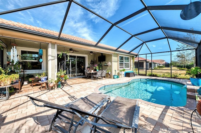 view of pool with glass enclosure, ceiling fan, and a patio area