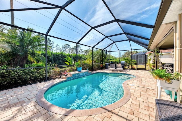 view of swimming pool featuring pool water feature, a lanai, a shed, a grill, and a patio