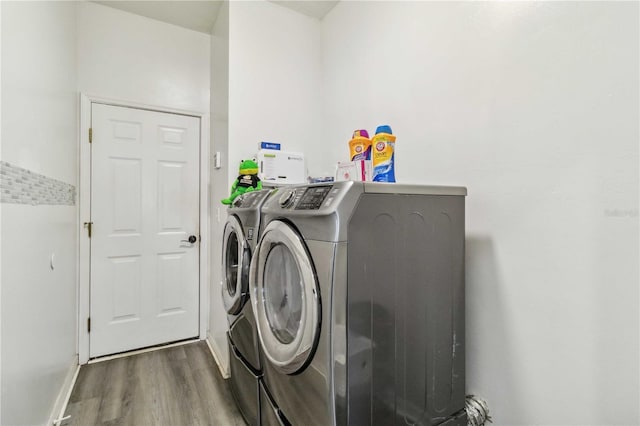 clothes washing area featuring washing machine and dryer and hardwood / wood-style flooring