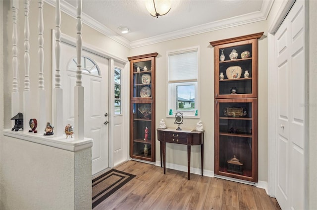 entryway with a textured ceiling, light wood-type flooring, and crown molding