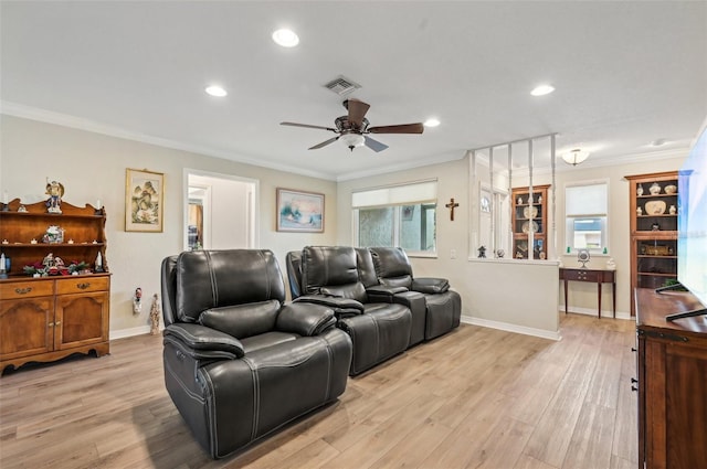 home theater room with ceiling fan, ornamental molding, and light wood-type flooring