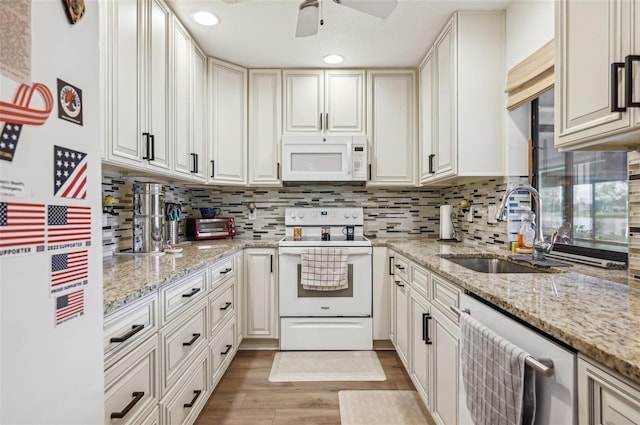 kitchen with light stone countertops, sink, light hardwood / wood-style floors, white appliances, and white cabinets