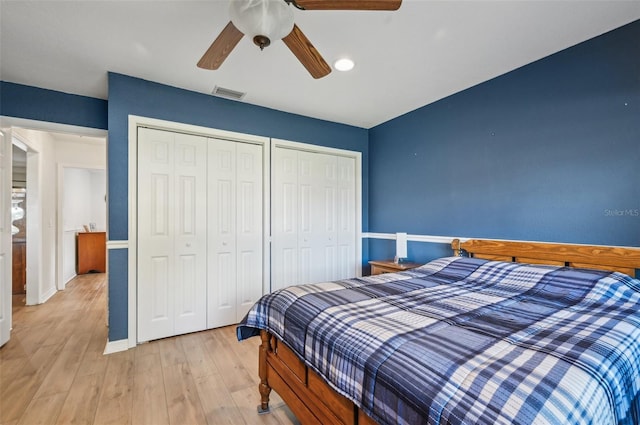 bedroom featuring ceiling fan, light wood-type flooring, and multiple closets