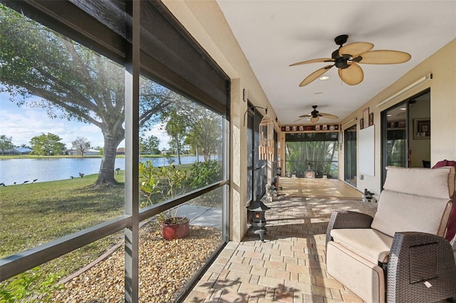 sunroom / solarium with ceiling fan and a water view