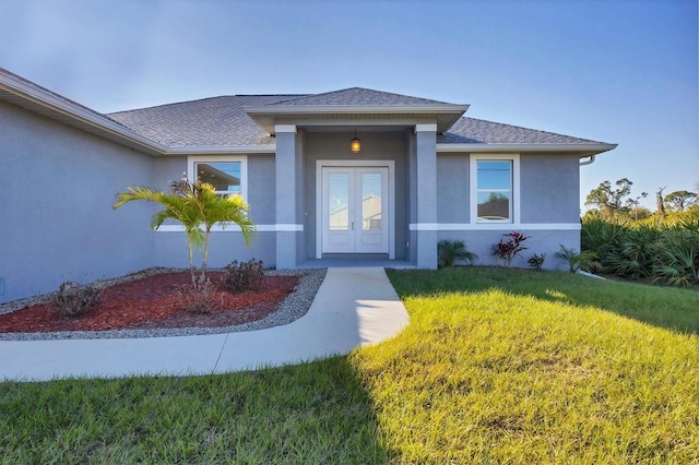 view of exterior entry with a lawn and french doors