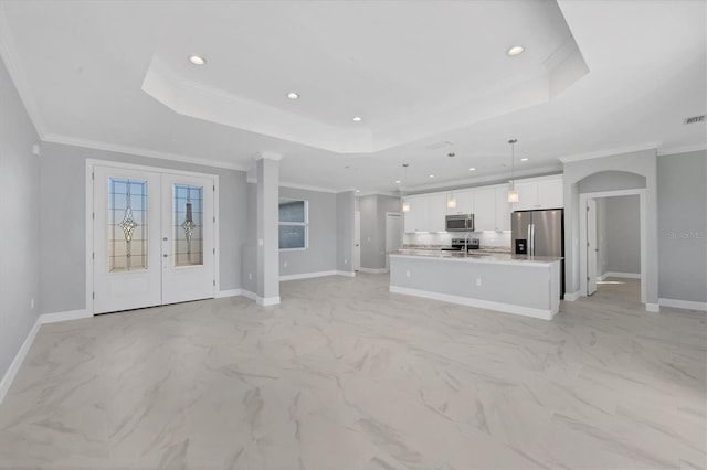 unfurnished living room featuring a tray ceiling, crown molding, and french doors