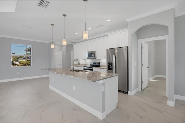 kitchen with white cabinets, crown molding, an island with sink, light stone counters, and stainless steel appliances