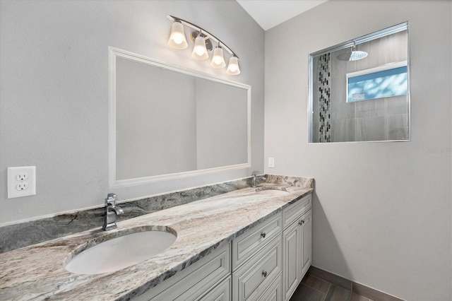 bathroom with a tile shower and vanity