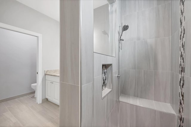 bathroom featuring vanity, toilet, and a tile shower