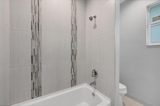 bathroom featuring tiled shower / bath and toilet