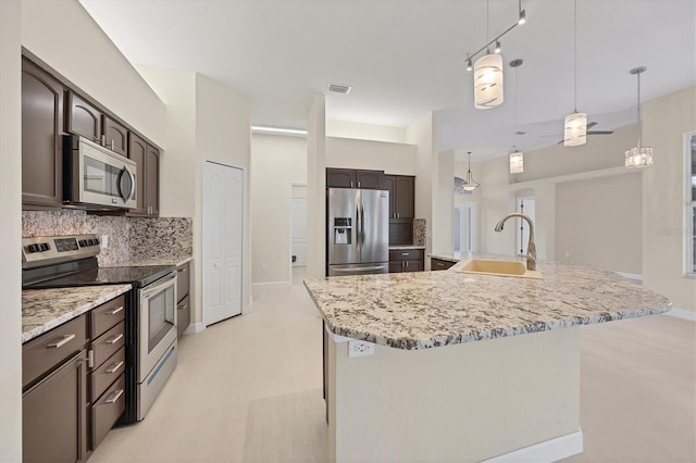 kitchen featuring a large island with sink, stainless steel appliances, ceiling fan, and sink