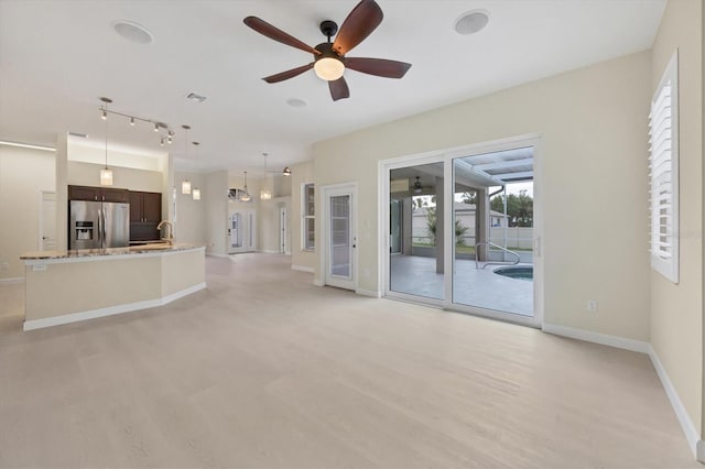 unfurnished living room with sink and ceiling fan with notable chandelier