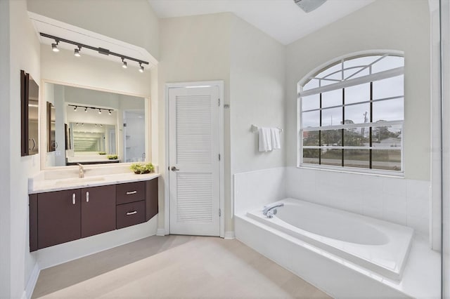 bathroom with vanity, a washtub, and vaulted ceiling