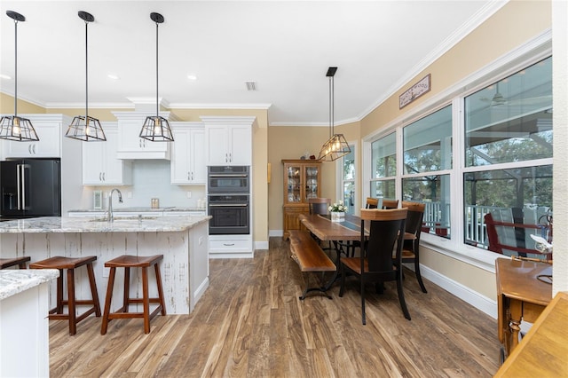 kitchen featuring light stone countertops, wood-type flooring, high quality fridge, decorative backsplash, and white cabinets