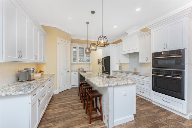 kitchen featuring sink, dark hardwood / wood-style floors, black double oven, a center island with sink, and white cabinets