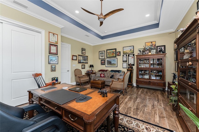 office area featuring a raised ceiling, crown molding, ceiling fan, and wood-type flooring