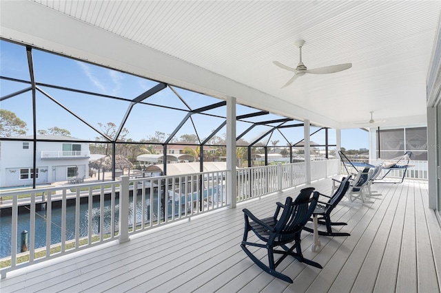 deck featuring ceiling fan, a water view, and glass enclosure