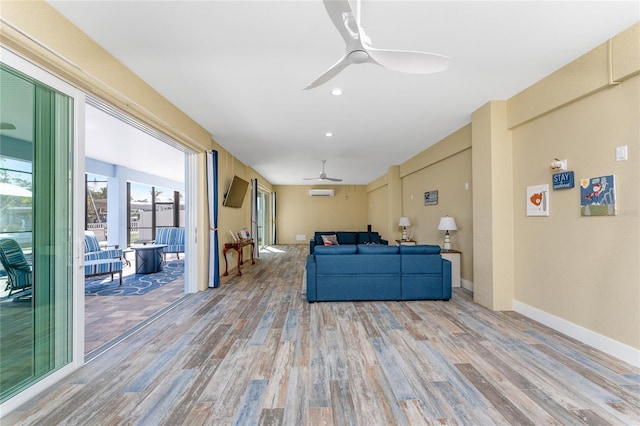 living room with an AC wall unit, ceiling fan, and light hardwood / wood-style flooring