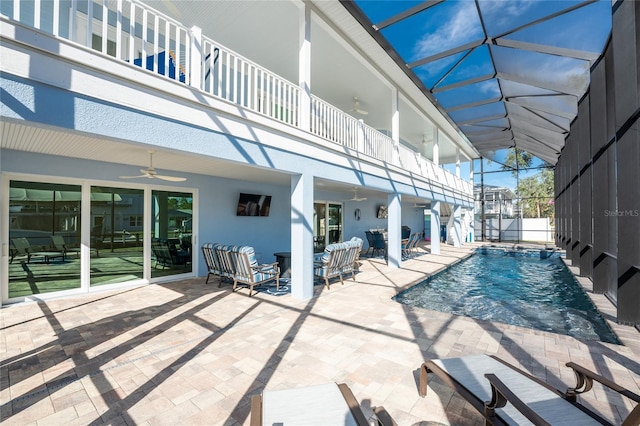 view of swimming pool with pool water feature, ceiling fan, a patio area, and glass enclosure