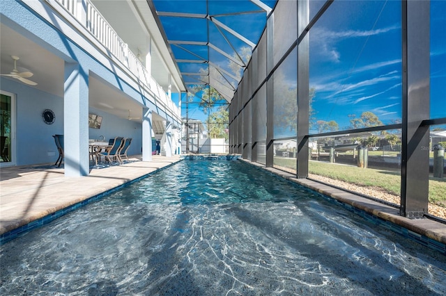 view of swimming pool featuring glass enclosure, ceiling fan, and a patio