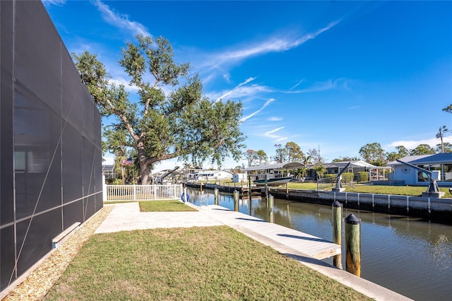 view of dock with a lawn, glass enclosure, and a water view