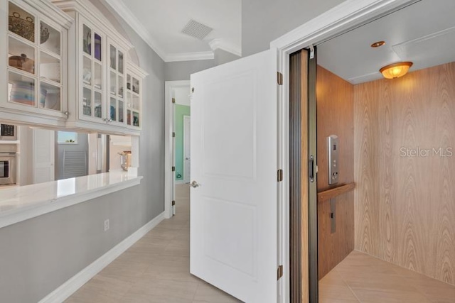 corridor with elevator, wooden walls, and crown molding