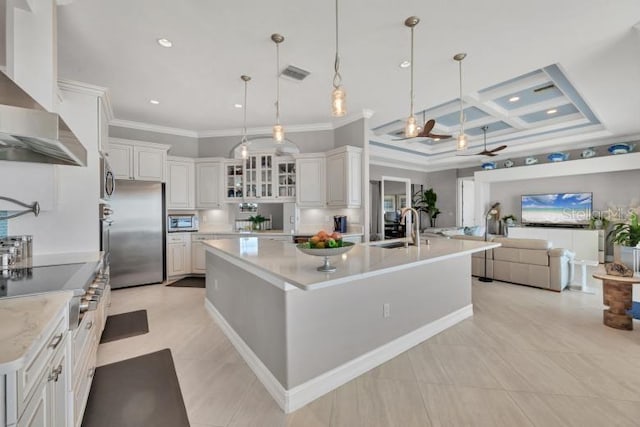 kitchen featuring wall chimney range hood, stainless steel fridge, a large island, and decorative light fixtures