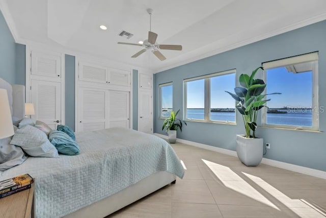 bedroom with multiple closets, ceiling fan, a water view, and ornamental molding