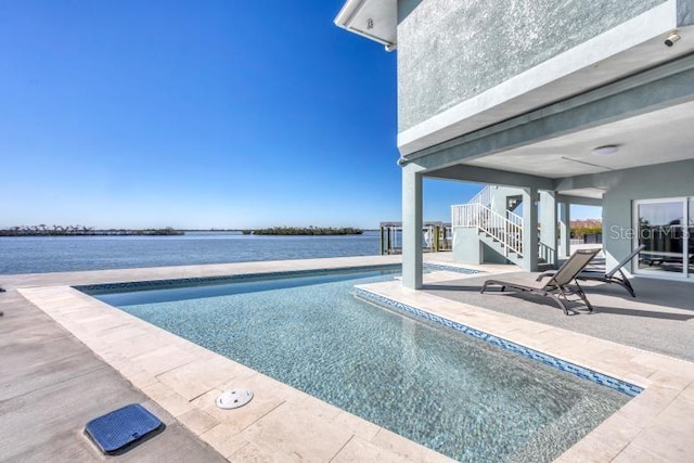 view of swimming pool featuring a water view and a patio