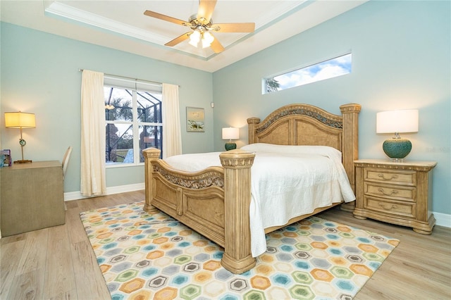 bedroom with a raised ceiling, ceiling fan, light hardwood / wood-style flooring, and crown molding