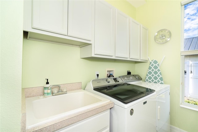 clothes washing area featuring separate washer and dryer, sink, and cabinets