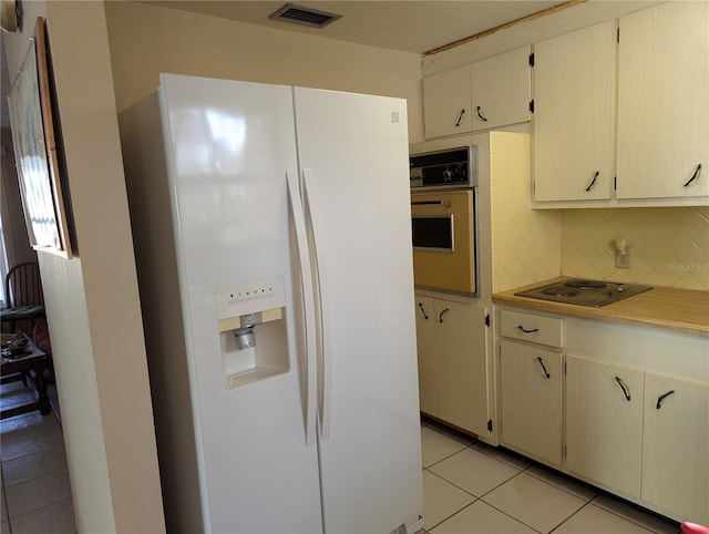 kitchen with white fridge with ice dispenser, oven, decorative backsplash, light tile patterned flooring, and electric stovetop