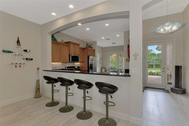 kitchen featuring tasteful backsplash, kitchen peninsula, appliances with stainless steel finishes, and pendant lighting