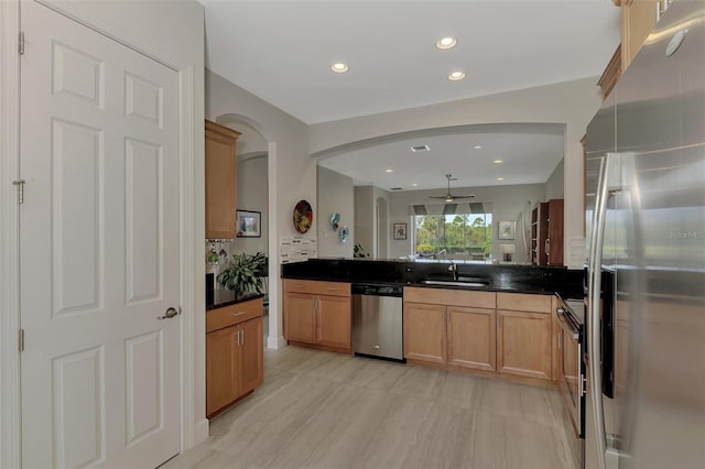 kitchen with kitchen peninsula, stainless steel appliances, backsplash, ceiling fan, and sink