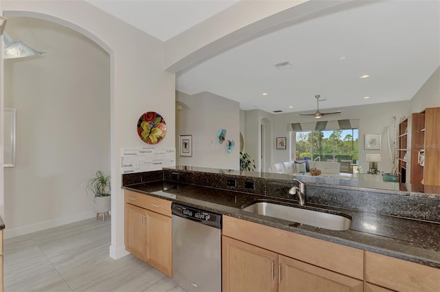 kitchen featuring dark stone countertops, ceiling fan, light brown cabinets, sink, and stainless steel dishwasher