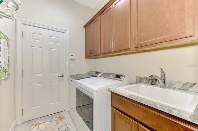 clothes washing area featuring cabinets, washing machine and clothes dryer, and sink